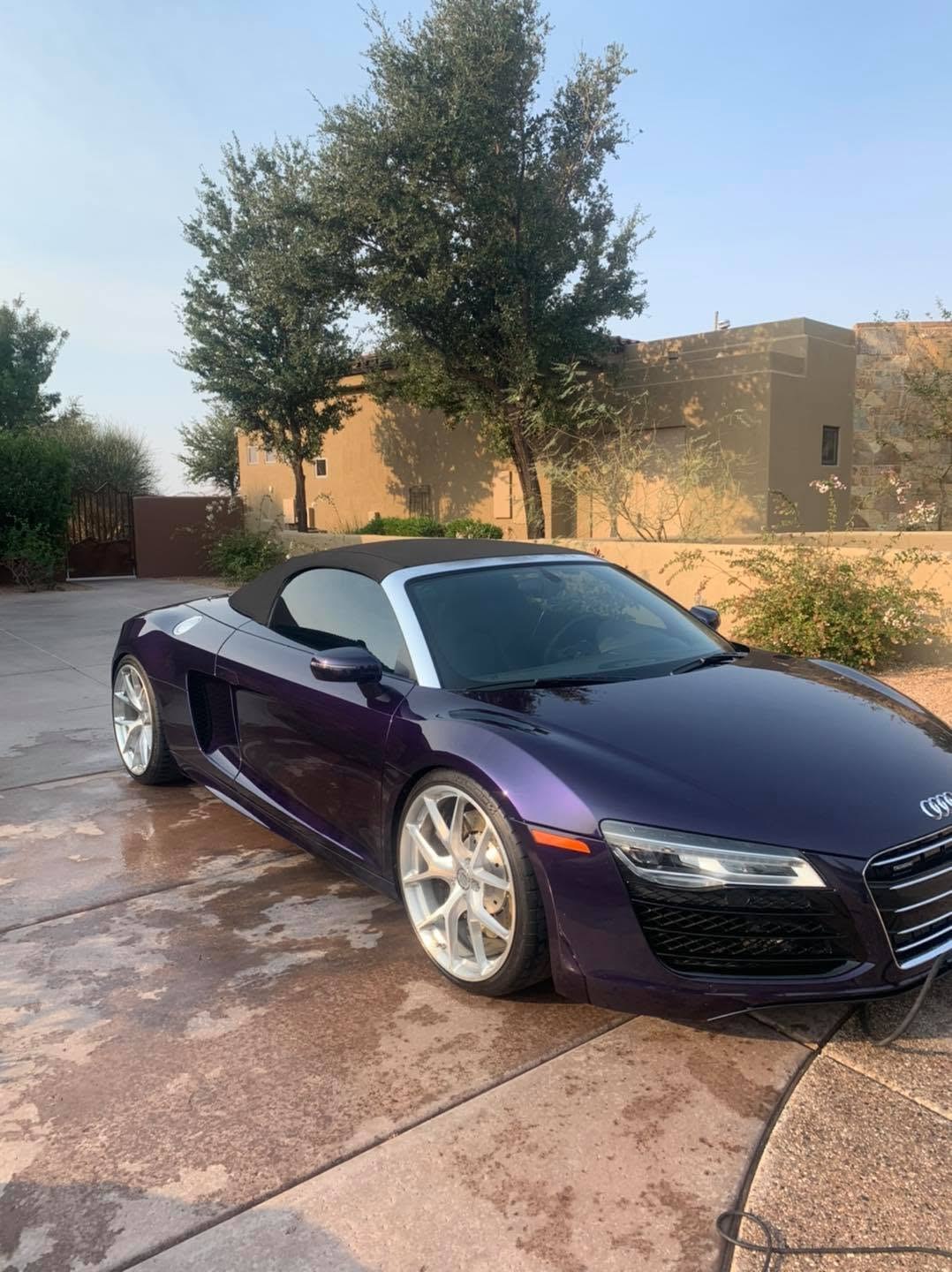 A dark plum Audi R8 Spyder detailed on a residential driveway
